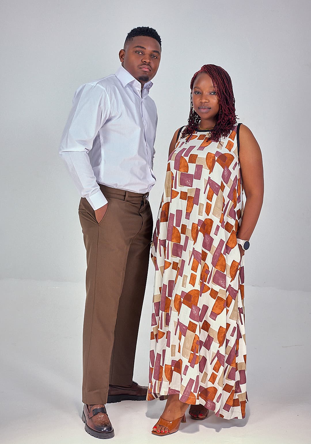 White shirt and brown trousers beside a print maxi dress